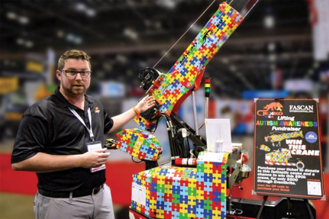 A man stands beside a minicrane, the surface of which is covered with a brightly-colored puzzle-piece design