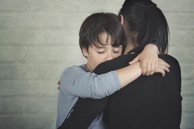 A sad boy is comforted by his mother.