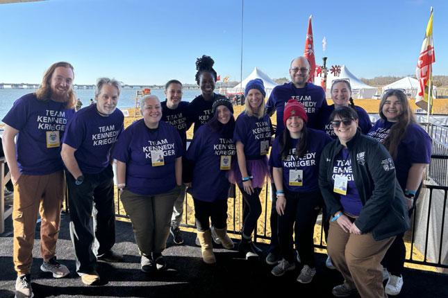 A group of Kennedy Krieger staff members smile while wearing purple Team Kennedy Krieger t-shirts.