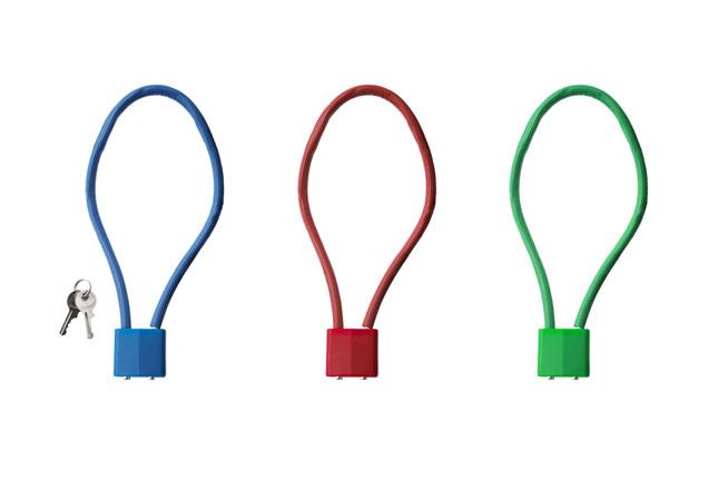 Blue, red and green safe storage locks lay side-by-side against a white background. A key is lying next to the blue lock.