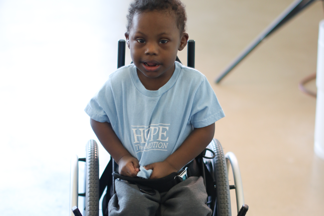 A young boy sits in a mobility device.