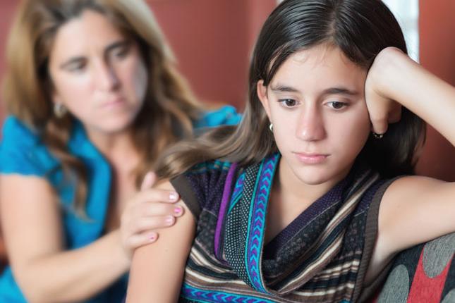 Una niña disgustada es consolada por una mujer adulta.