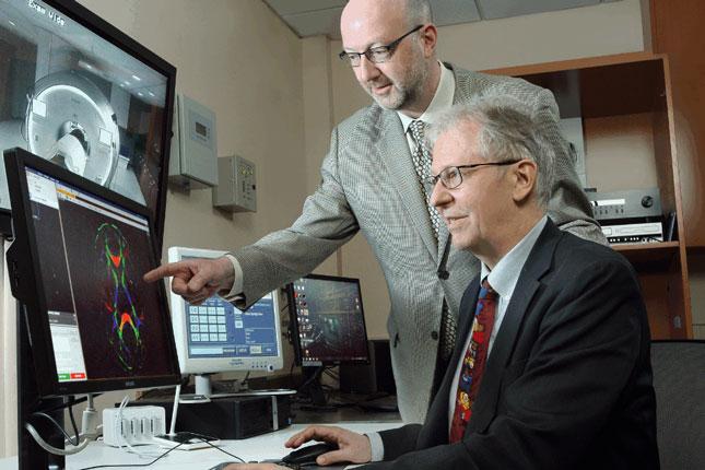 Drs. from the F.M. Kirby Center at Kennedy Krieger Institute look at data a monitor.
