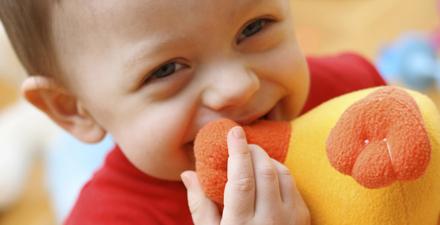 A child playing with a stuffed animal.