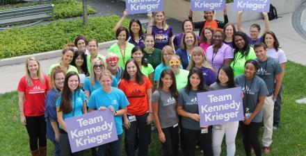 A group of Kennedy Krieger employees, wearing Kennedy Krieger shirts and holding signs that read, "Team Kennedy Krieger"