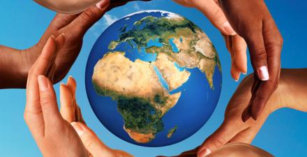 Hands around a globe, with blue sky in the background.