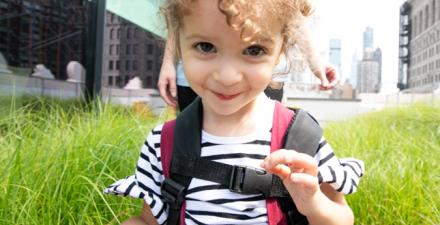 A young girl stands close to the camera and smiles.