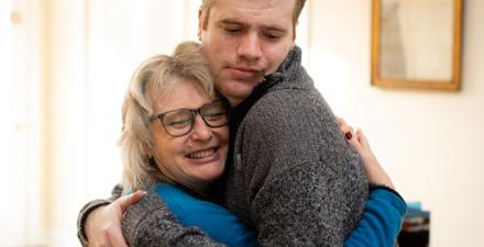 A mother hugs her adult son.