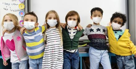 Six young children wearing facemasks in their classroom. 