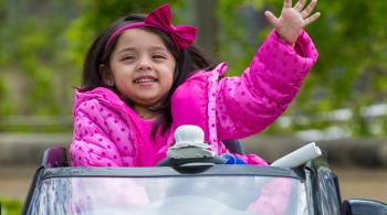 3-year old patient Sanayah waves from a modified car