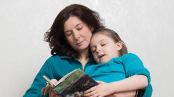 Caetlyn lays in her mom, Caryn's lap, as Caryn reads a book to her.