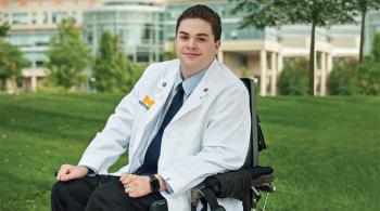 Chris Connolly poses wearing his University of Michigan Medical School white coat