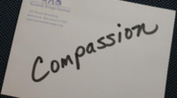 A piece of paper with the word "Compassion" written across it in black