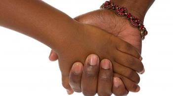A photograph of a child's hand holding the hand of an adult