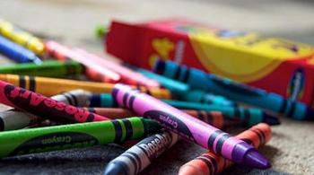 A photograph of crayons atop a rug, sitting next to the crayon box