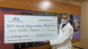 Dr. Ali Fatemi holds large check during the Cure for Ellie Check presentation 2021.