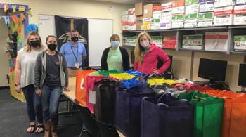 Kennedy Krieger staff members stand behind bags that were packed as part of an Act for Kindness. 