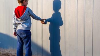 A boy with autism looks at his shadow. 