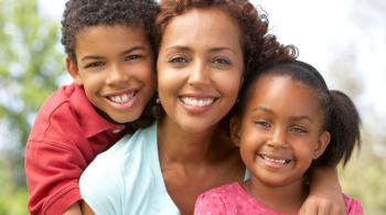 A mother and her two children smile brightly.