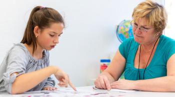 A young girl works on a project with her therapist.
