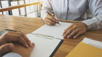 Two people look over paperwork in a professional setting.