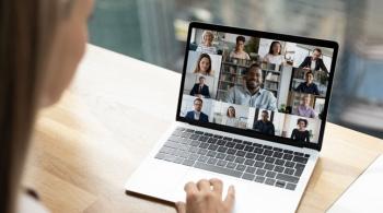 Close up back view of woman participating in online video call with colleagues.