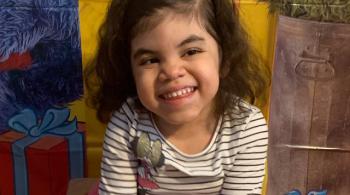 Violet smiles while sitting in a small chair.