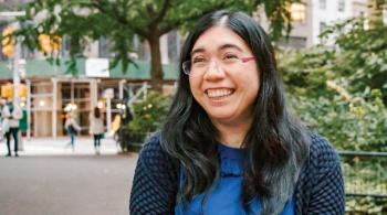 Valerie, smiling, sits in a wheelchair in an urban setting