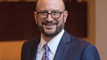 Portrait photo of a man wearing glasses and a suit and tie