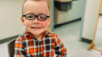 A young boy with Sturge-Weber syndrome, a rare disease, sits at a table and smiles. 