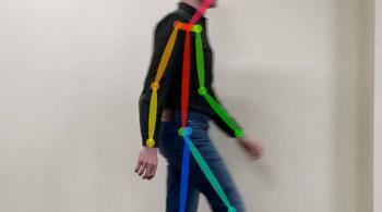 A man walks against a blank wall. Colorful lines are shown over his body, helping researchers analyze his walking and gait. 