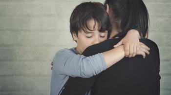A sad boy is comforted by his mother.
