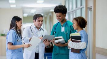 A group of doctors and nurses have a conversation in the hallway of a hospital.