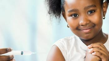 A young girl smiles while receiving a vaccine.