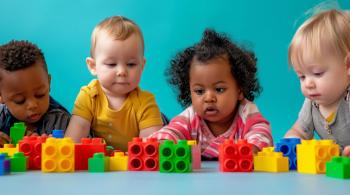 Four toddlers play with colorful blocks sitting on a table.