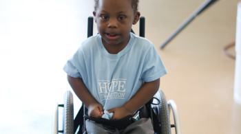 A young boy sits in a mobility device.