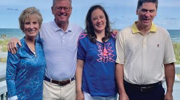 The Lewis family poses for a photo outside, with a beach in the background.