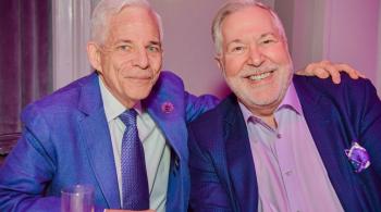 Patrick and Howard smile while sitting at a banquet table.