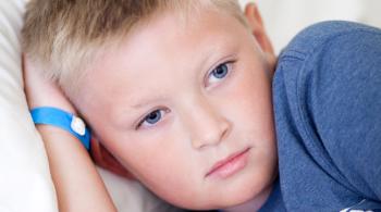 A boy with a sad expression on his face rests against a pillow.