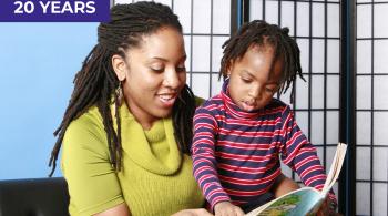 A young woman reads to a little boy, who points to something on the page of the book.