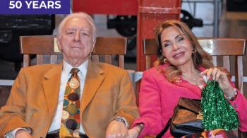 Dr. Michael and Marilyn Cataldo relax on wooden rocking chairs. They are both smiling.