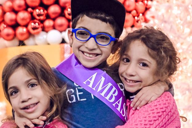 A Kennedy Krieger ambassador and his sisters smile at Festival of Trees.