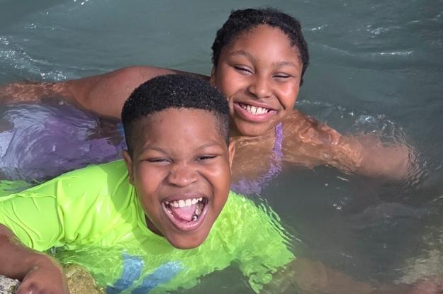 A Kennedy Krieger ambassador and his sister smile while swimming.
