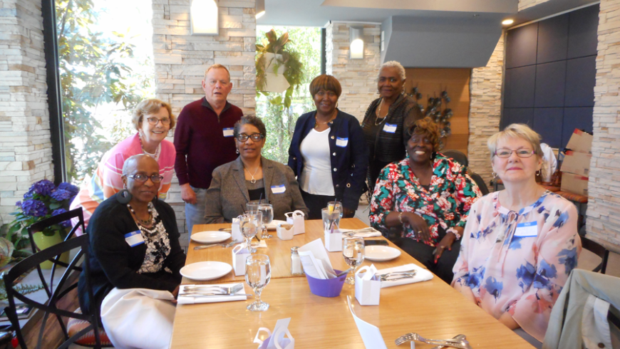 A group of eight, seven women and one man, around a table. 