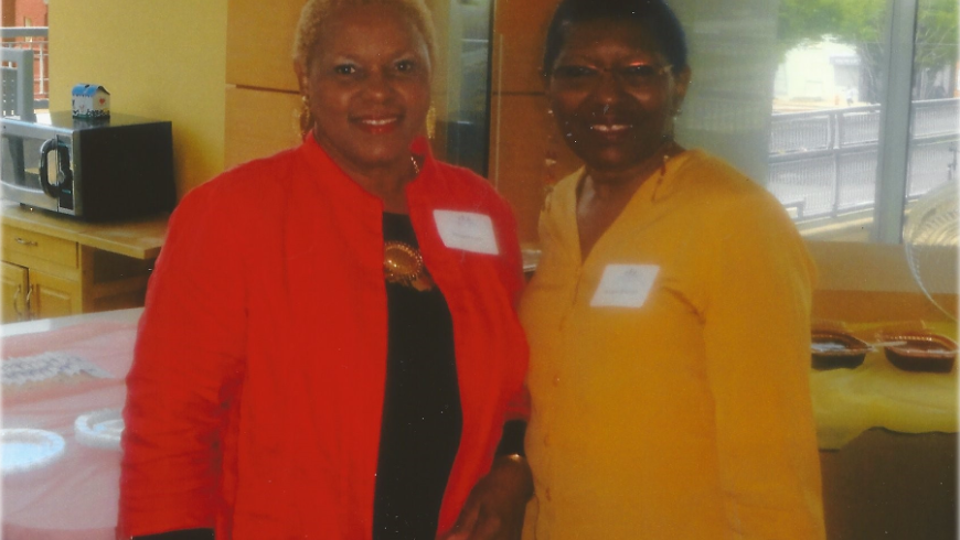 Two women stand and pose for a photo. 