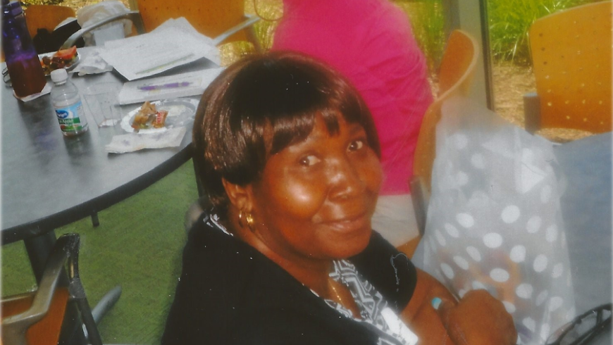 A woman smiles at the camera while sitting at her table.