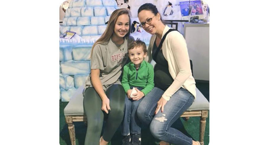 A woman and two children pose for a photo at Festival of Trees.