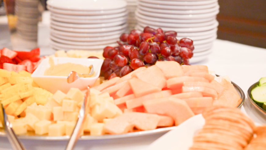 A platter of food that includes cheese, grapes and strawberries