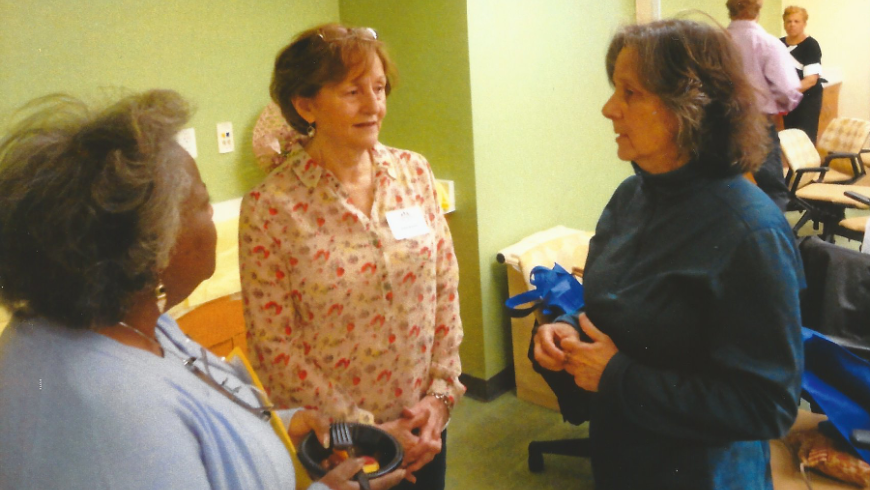 Three women have a conversation. 