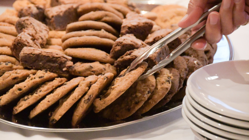 A cookie is removed from a plate with a pair of tongs.